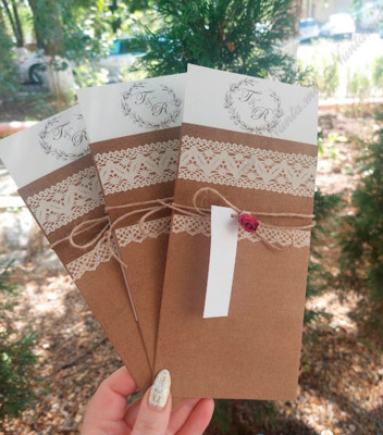 <p>Invitație de nuntă realizată din carton crem destinat imprimării textului. Invitația este introdusă într-un carton de tip buzunar, ornamentat cu elemente de tip dantelă și accesorizat cu o fundiță din sfoară de cînepă, de care atîrnă o etichetă prinsă cu un trandafir roșu. În calitate de plic servește o folie transparentă cu adeziv dublu.</p>