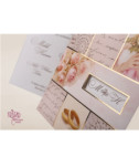 <p>Invitație de nuntă realizată din două părți. Prima parte cartonul de culoare albă pe care se imprimă textul și care se introduce în partea a doua, un suport tip buzunar confecționat din carton cu motiv floral, în care este decupată o fereastră prin care se văd inițialele mirilor. Ca accesoriu are o panglică roz.</p>