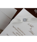 <p>Invitație de nuntă realizată dintr-un carton de culoare albă, cu un model sidefat la colțuri. Invitația este accesorizată cu o fundiță elegantă albă. Plicul invitației este de culoare albă și introdus în preț.</p>
